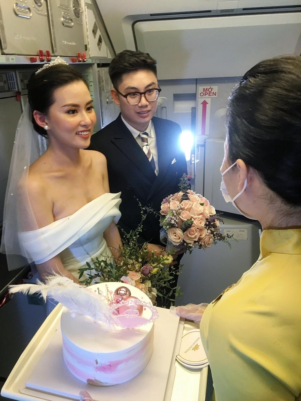 Tiếp viên trưởng chuyến bay thay mặt phi hành đoàn và hành khách tặng quà kỷ niệm cho cặp đôi Tiếp viên trưởng chuyến bay thay mặt phi hành đoàn và hành khách tặng quà kỷ niệm cho cặp đôi